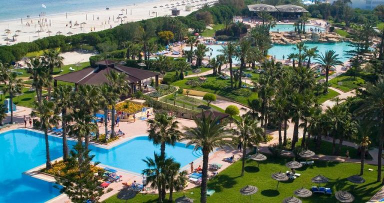 Vista aérea de las piscinas exteriores y jardines tropicales del Sahara Beach Aquapark Resort con playa