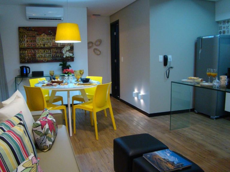 Salón comedor moderno con sillas amarillas y cocina integrada en Flat 508 Recife