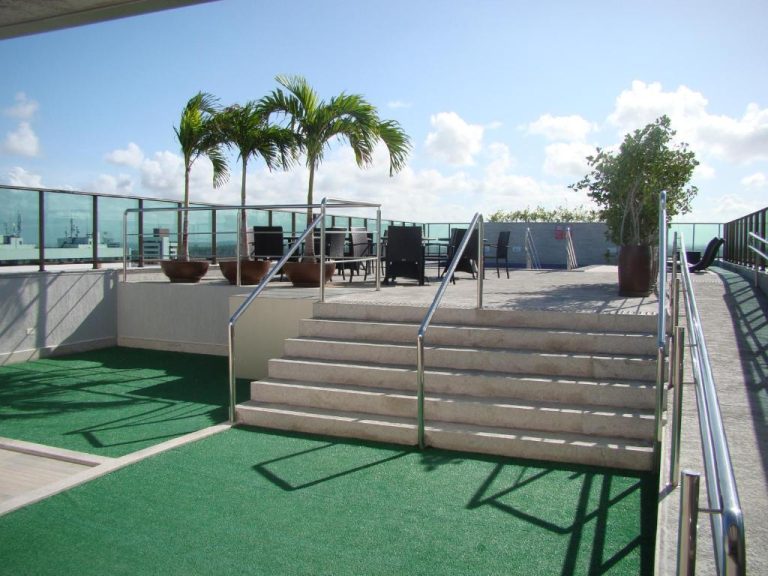 Terraza exterior con escaleras, palmeras y zona de descanso en la azotea del Flat 508 Recife