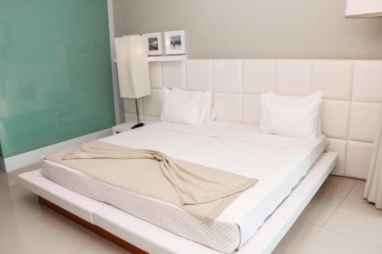 Habitación doble con cama king size y cabecero tapizado blanco en Hotel Vip Praia