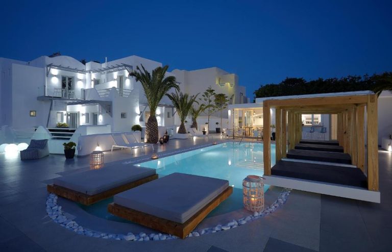 Piscina exterior iluminada de noche con tumbonas y palmeras en Callia Retreat Suites Adults Only