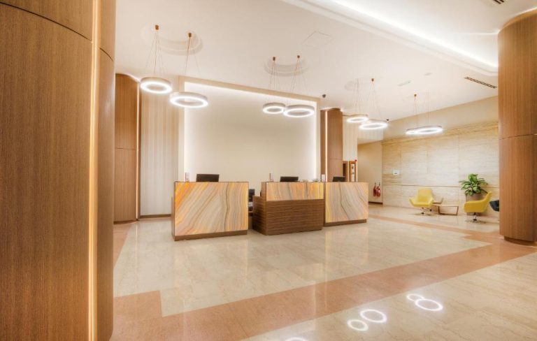Recepción principal del Vivaldi Hotel con mostradores de mármol iluminados y lámparas circulares modernas