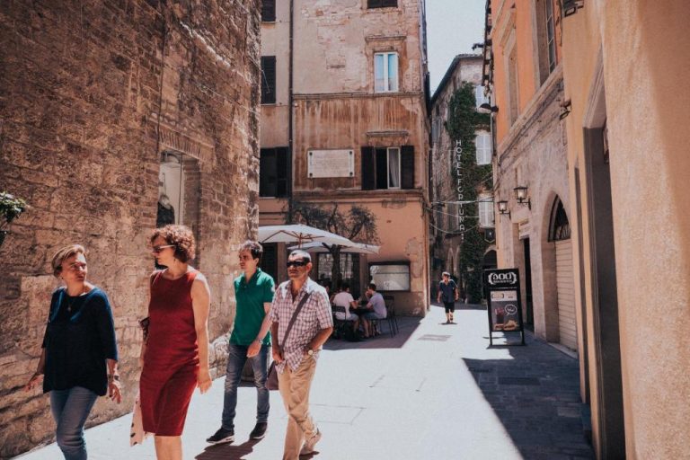 Turistas paseando por la calle histórica frente al Hotel Fortuna en el centro medieval de la ciudad