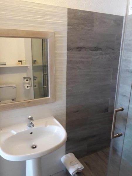 Baño moderno con ducha de cristal y lavabo en Tropical Sunset Beach Apartment Hotel