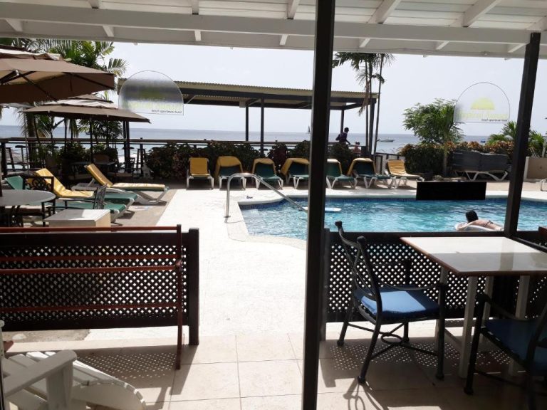 Piscina exterior con tumbonas y terraza frente al mar en Tropical Sunset Beach Apartment Hotel