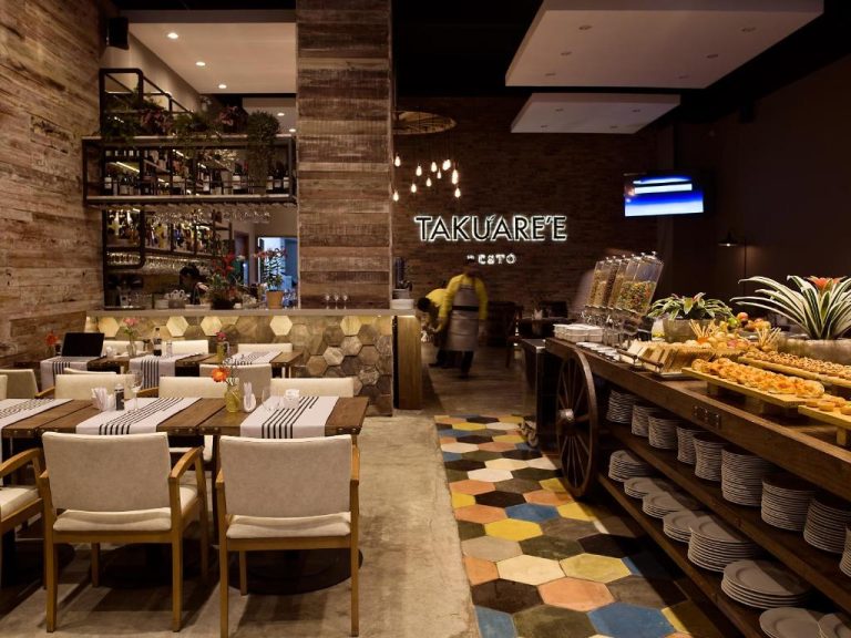 Restaurante Takuare'e del Dazzler by Wyndham Asunción con buffet, barra y decoración rústica moderna
