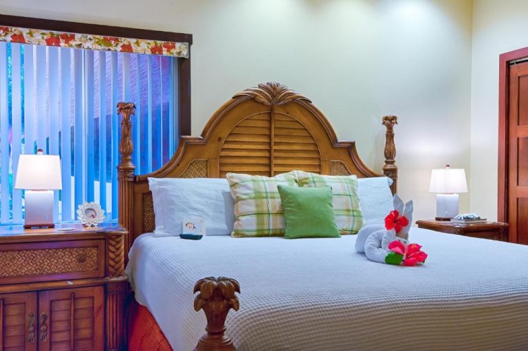 Habitación con cama king size y cabecero de madera tallada en Infinity Bay Spa & Beach Resort