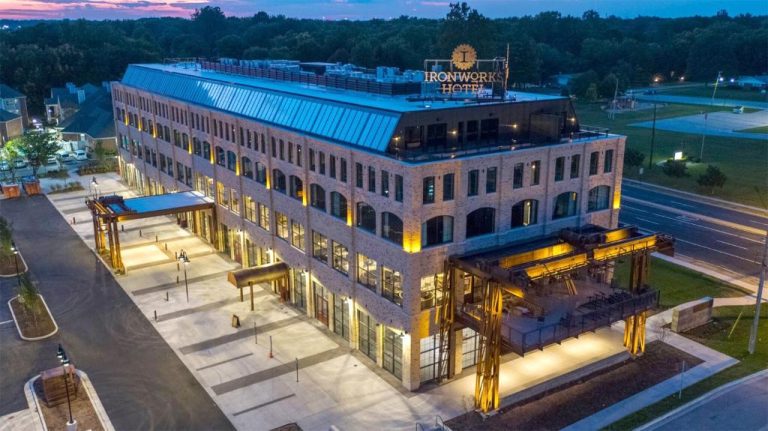 Vista aérea nocturna de la fachada exterior de ladrillo del Ironworks Hotel Indy con iluminación cálida