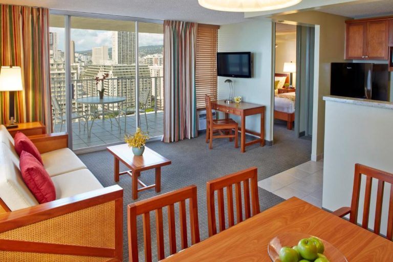Suite con salón, comedor y vistas panorámicas a la ciudad en el Pacific Monarch Hotel de Honolulu