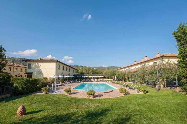 Piscina exterior rodeada de jardín y tumbonas del Relais dell'Olmo en la Toscana italiana