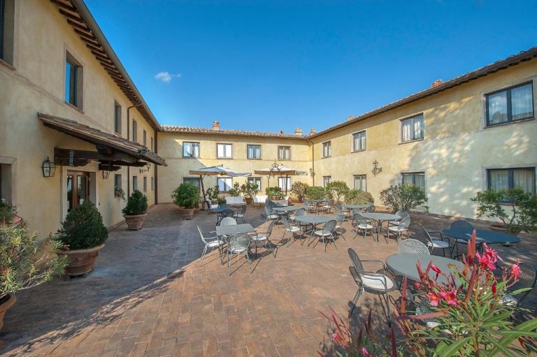 Terraza exterior con mesas y sillas en el patio interior del Relais dell'Olmo en Toscana