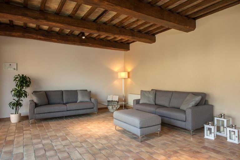 Salón con sofás grises y vigas de madera en el techo del Relais dell'Olmo en Toscana