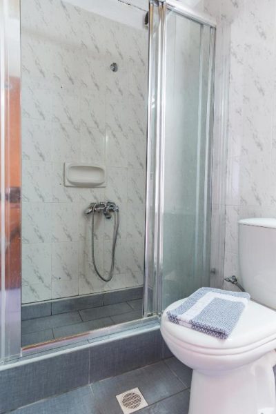Baño con ducha de mampara de cristal y aseo en el Daskalogiannis Hotel