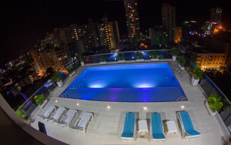 Piscina iluminada en la azotea del Hotel Tayrona del Mar con vista panorámica nocturna de la ciudad