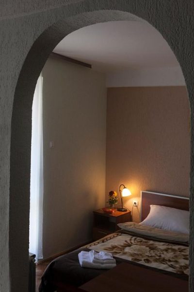 Habitación doble con arco decorativo y cama matrimonial iluminada en Hotel Djokovic