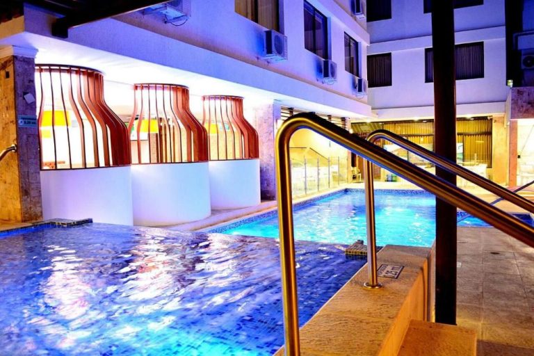 Piscina interior climatizada con jacuzzi y barandillas doradas del Hotel La Riviera