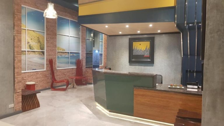 Recepción moderna del Hotel GQ Plaza con mostrador verde y decoración en ladrillo visto