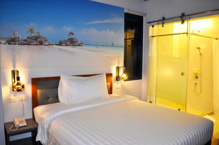 Habitación doble del GQ Plaza con mural de playa tropical, cama king y ducha de cristal independiente