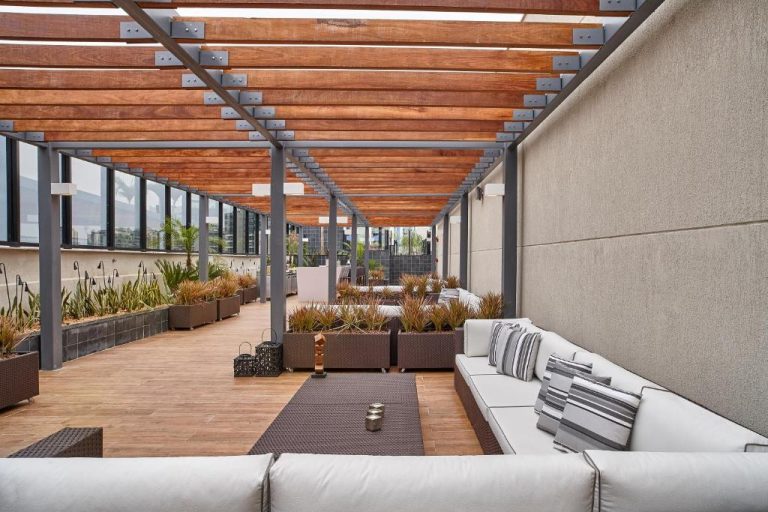 Terraza lounge exterior con pérgola de madera y sofás blancos en Radisson Rio de Janeiro Barra