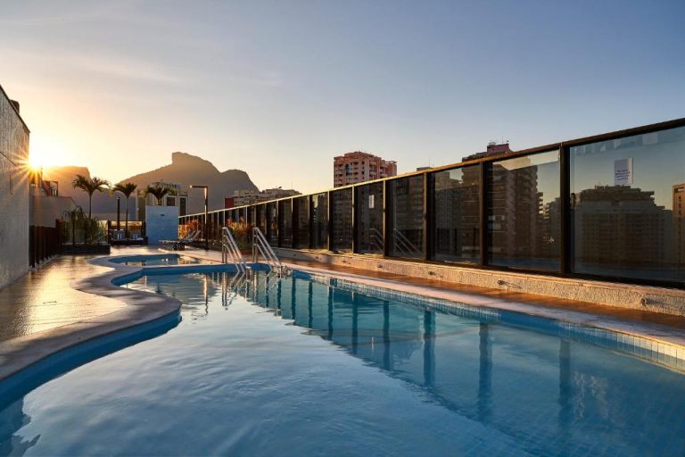 Piscina exterior en la azotea del Radisson Rio de Janeiro Barra con vistas al skyline y montañas al atardecer