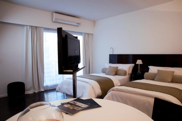 Habitación twin con dos camas, televisor giratorio y aire acondicionado en Awwa Suites & Spa