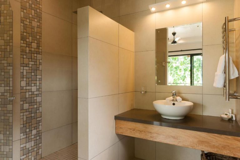 Baño moderno con lavabo sobre encimera de madera y ducha de mosaico en Le Repaire Boutique Hotel