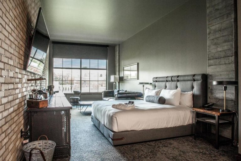 Habitación con diseño industrial, cama king y paredes de ladrillo en Ironworks Hotel Indy