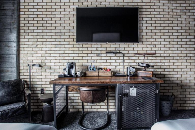 Escritorio de madera estilo industrial con cafetera y TV en habitación del Ironworks Hotel Indy