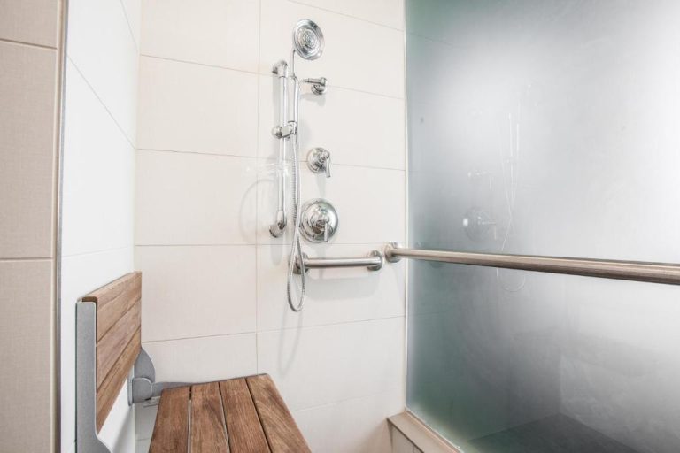 Ducha accesible con asiento de madera y barras de apoyo en el Ironworks Hotel Indy