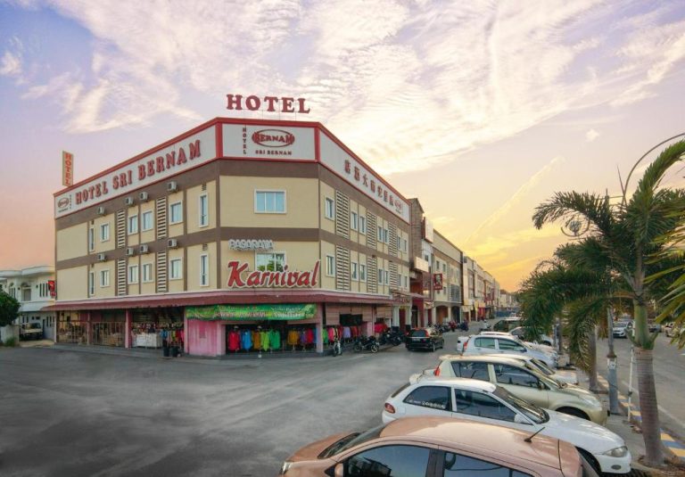 Fachada exterior del Hotel Sri Bernam con aparcamiento y tienda Karnival al atardecer