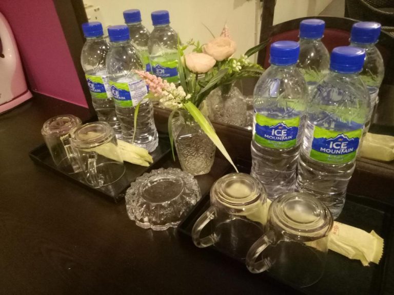 Botellas de agua Ice Mountain y vasos de cristal en la habitación del Hotel Sri Bernam