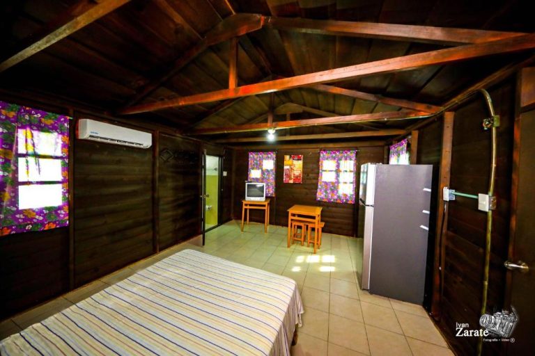 Habitación rústica de madera con cama, refrigerador y aire acondicionado en ECO-CABAÑAS Cancún