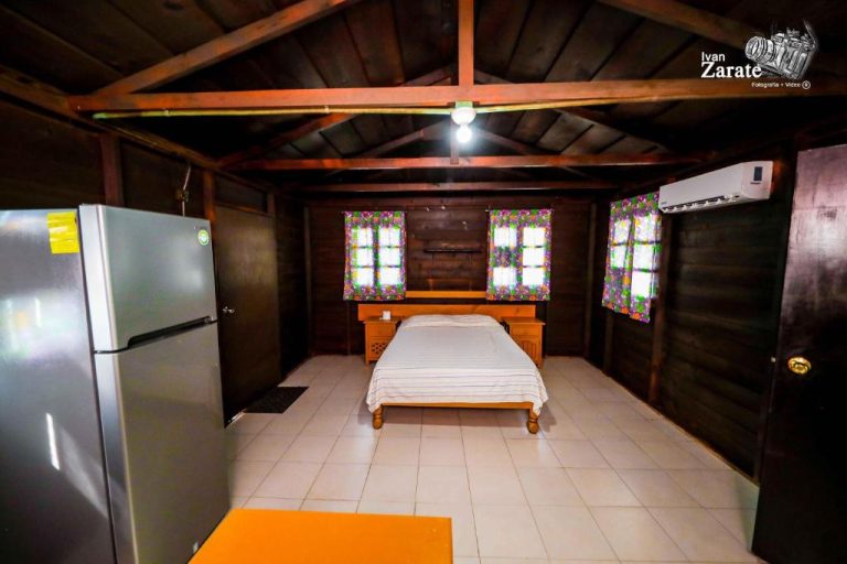 Habitación rústica de madera con cama doble, refrigerador y aire acondicionado en ECO-CABAÑAS Cancún