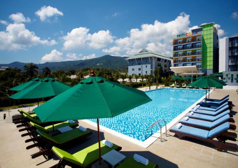Piscina exterior con tumbonas y sombrillas verdes del Hotel Samui Verticolor en Tailandia