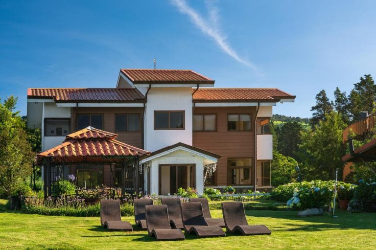 Jardín exterior con tumbonas y gazebo del Altura Hotel rodeado de vegetación y cielo azul