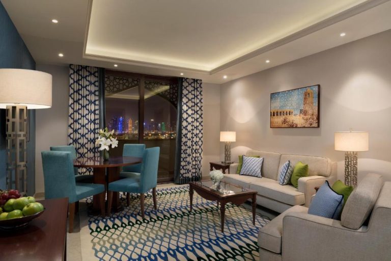 Salón comedor moderno con vistas nocturnas a la ciudad en Al Najada Doha Hotel Apartments by Oaks