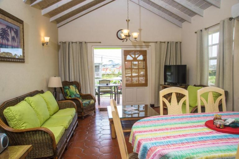 Sala de estar y comedor tropical con sofás verdes y mesa en Best E Villas Prospect St James