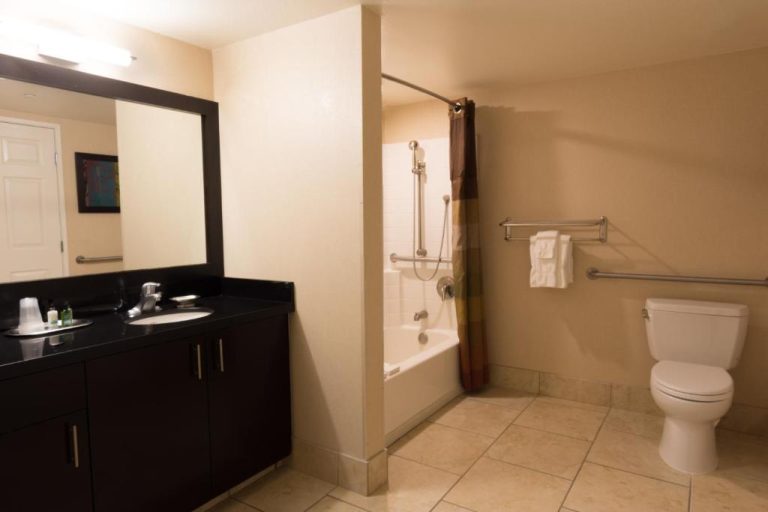 Baño accesible con bañera, ducha adaptada y lavabo en The Carriage House Hotel