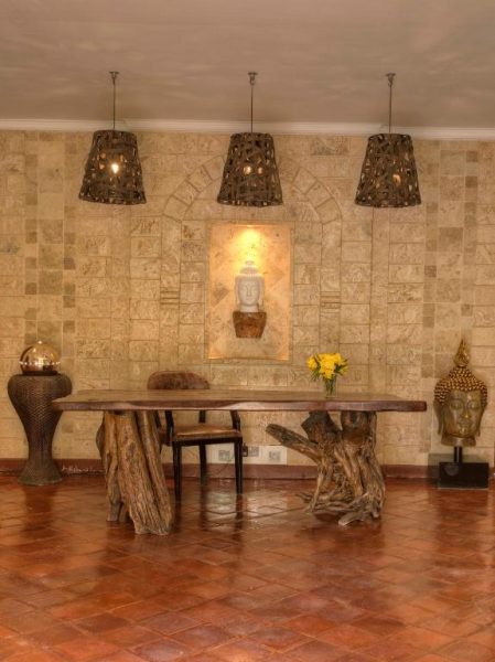 Lobby del Aberdare Country Club con mesa de troncos naturales, esculturas Buddha y lámparas decorativas