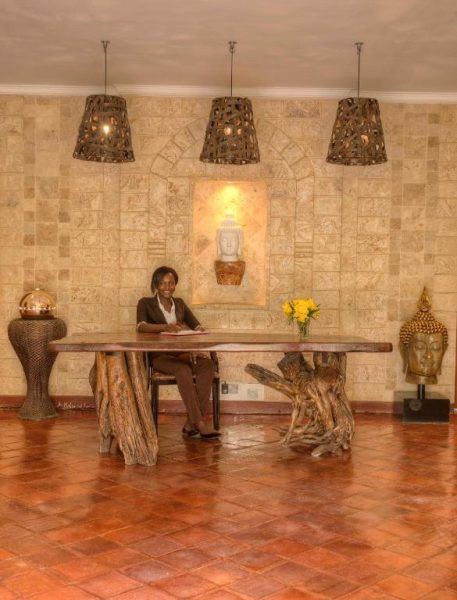 Recepción del Aberdare Country Club con mesa de madera artesanal y decoración budista exótica