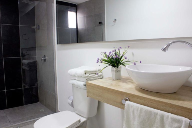 Baño moderno con lavabo sobre encimera de madera y ducha acristalada en Hotel Boutique Plaza