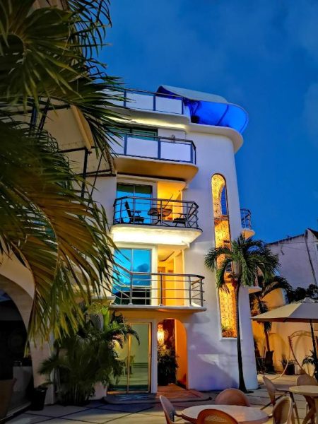 Fachada exterior iluminada del Hotel Blue Star Cancun con terrazas y rooftop azul durante la noche