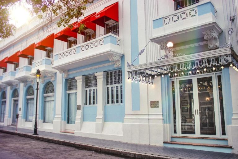 Fachada colonial azul y blanca del Hotel Meliá Ponce con balcones y toldos rojos en Puerto Rico