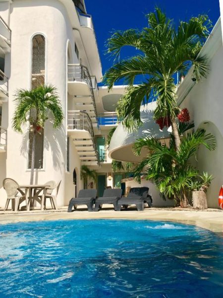 Piscina exterior con tumbonas y palmeras del Hotel Blue Star Cancún rodeada de edificio blanco