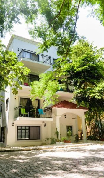 Fachada exterior de Che Suites Playa con balcones y vegetación tropical en Playa del Carmen