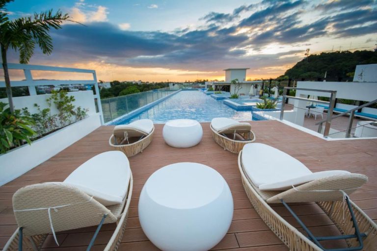 Terraza con piscina infinita y tumbonas de diseño al atardecer en Ferra Hotel and Garden Suites