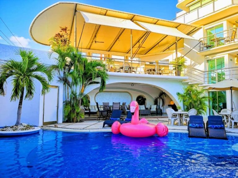 Piscina exterior con flotador flamingo rosa del Hotel Blue Star Cancun rodeada de palmeras y tumbonas