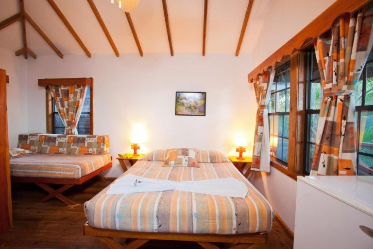 Habitación doble con dos camas y techo de vigas de madera en Las Rocas Resort and Dive Center
