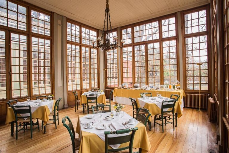 Elegante salón comedor del Hotel Casa Real Viña Santa Rita con mesas amarillas y grandes ventanales de madera