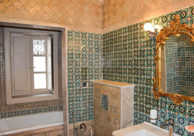 Baño decorado con azulejos arabescos en verde y espejo dorado barroco en Dar Alouini